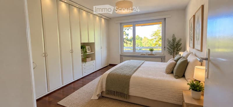 Modern bedroom with a large bed, nightstand, lamp, potted plant, and a large wardrobe. The room features large windows with a view of greenery outside.