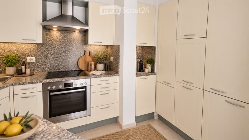Modern kitchen with white cabinets, stainless steel appliances, granite countertops, and decorative items including potted plants and a bowl of lemons.