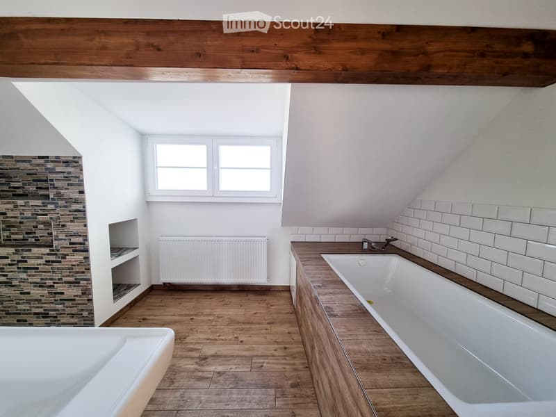 Bathroom with wooden flooring, white tiled walls, two bathtubs, a radiator, and a window with double panes.