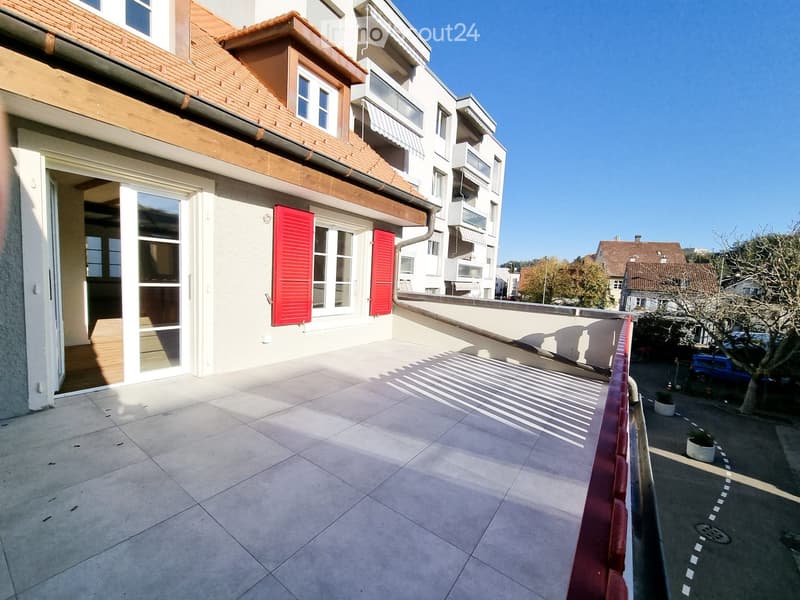 Balcony with tiled floor, red railing, and view of neighboring buildings and a parked car.