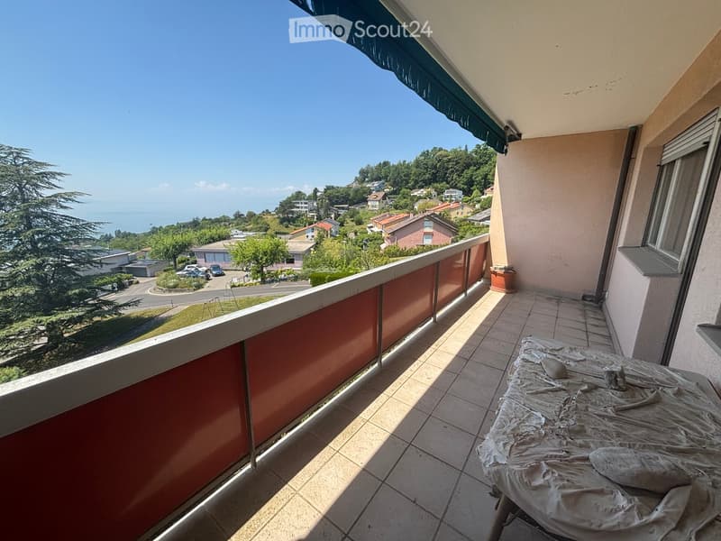 Balcony with tiled floor, red railing, and scenic view of a town and sea.