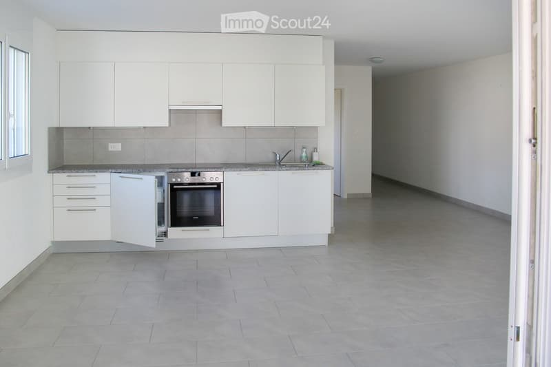 Modern kitchen with white cabinets, stainless steel oven, granite countertop, and tiled floor.