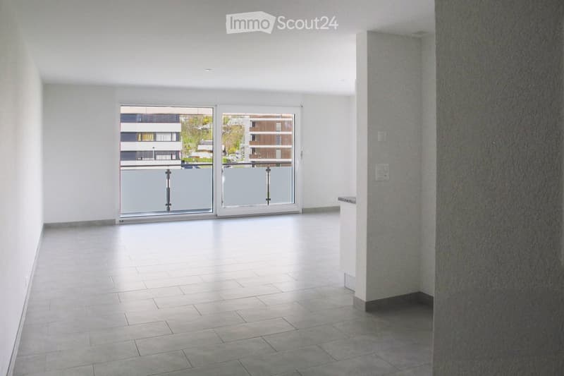 Empty room with tiled floor, white walls, and large glass doors leading to a balcony.