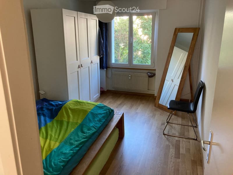 white wardrobe, bed, wooden floor, large mirror, chair, white wall, window, radiator