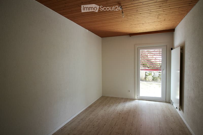 Empty room with wooden flooring, white walls, and a sliding glass door leading to an outdoor area.