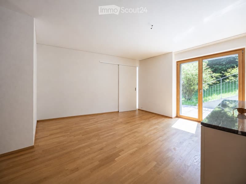 Empty room with light wooden flooring, white walls, and large sliding glass doors leading to an outdoor area.