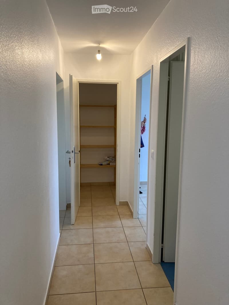 Empty hallway with tiled floor, white walls, and several open doors leading to other rooms.