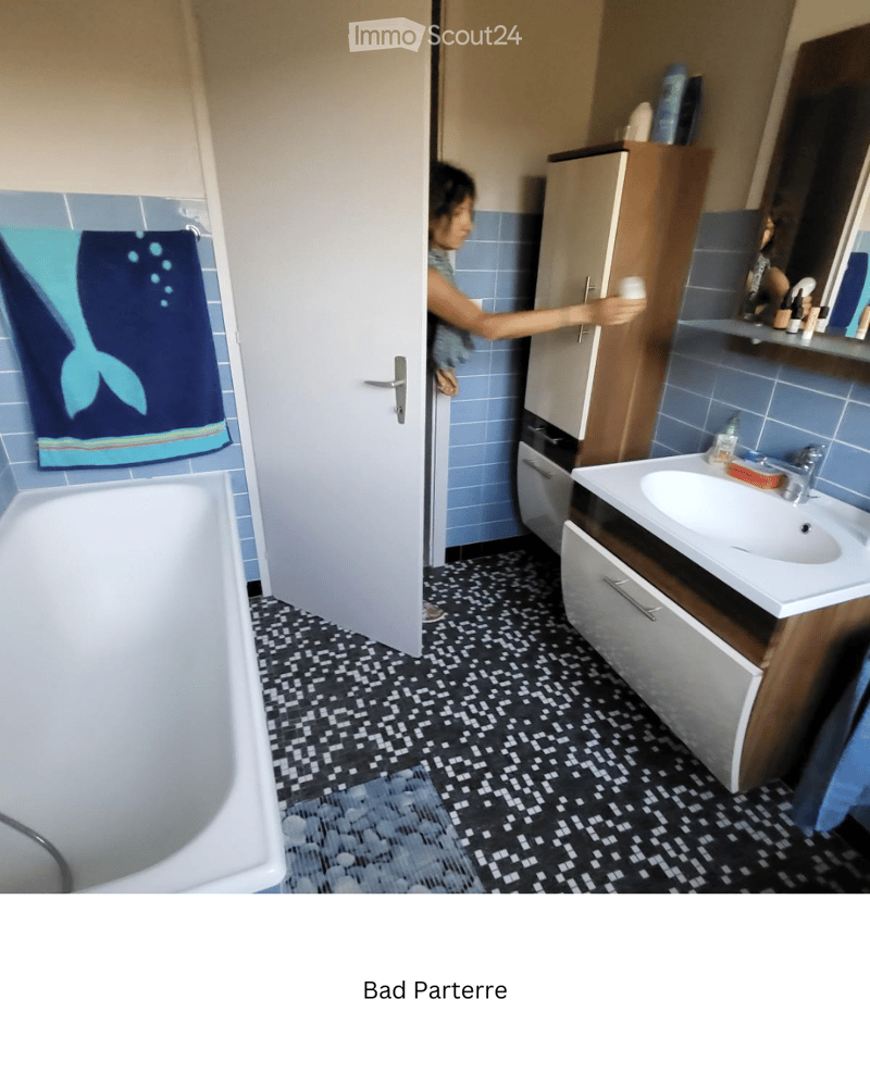 Bathroom with blue tiles, black and white patterned floor, bathtub, sink with mirror, and cabinet.