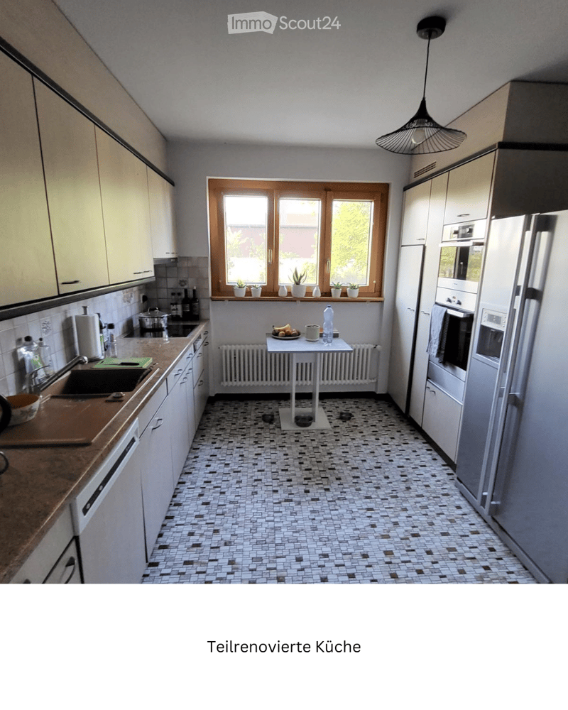 Partially renovated kitchen with white cabinets, stainless steel appliances, a small round table, and various kitchen items on the counter and windowsill.