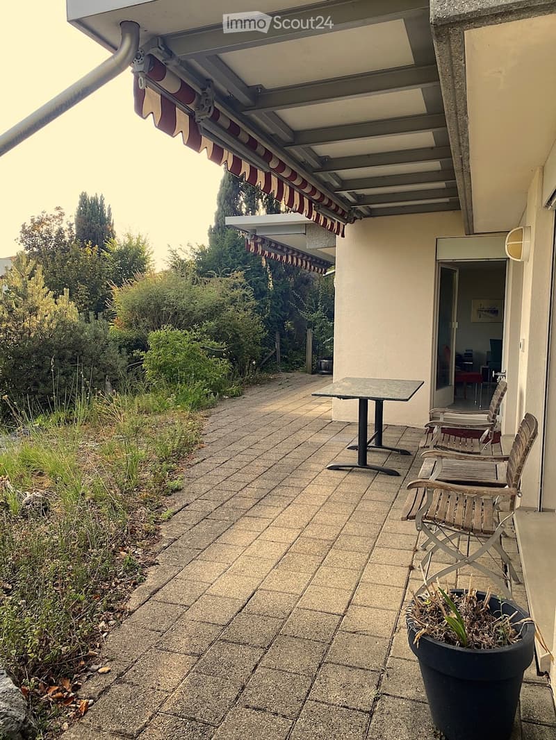 Balcony with tiled floor, table, chairs, and a covered awning extending from the building.
