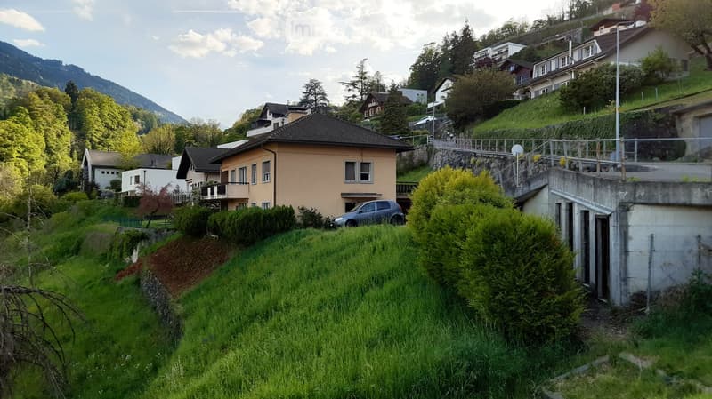 Residential area with multiple houses, greenery, and a car parked in front of one house.
