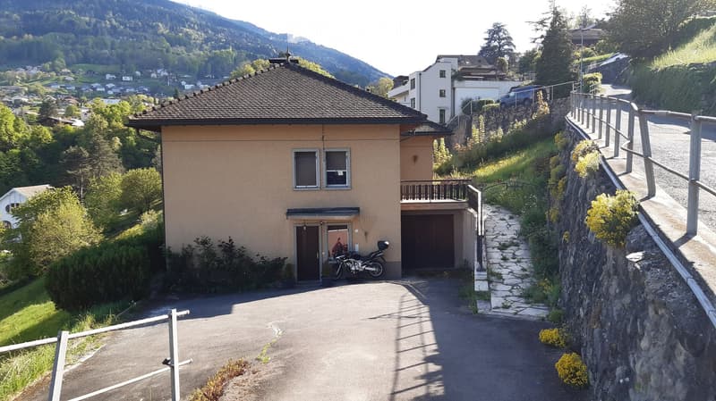 Two-story house with a garage, balcony, and scenic mountain view in the background.