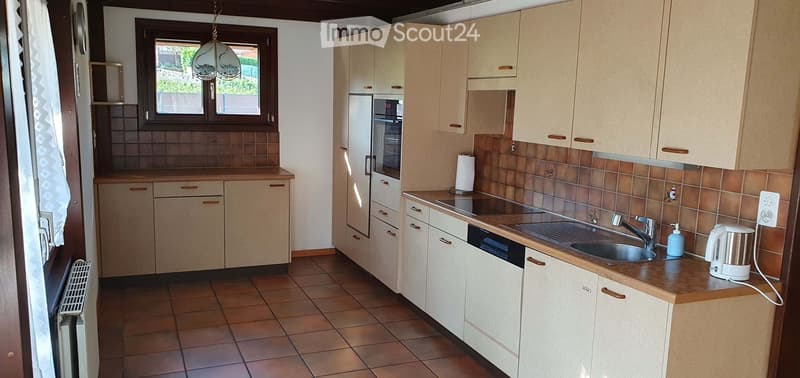Modern kitchen with light wood cabinets, tiled backsplash, stainless steel sink, and appliances including a refrigerator, oven, and dishwasher.