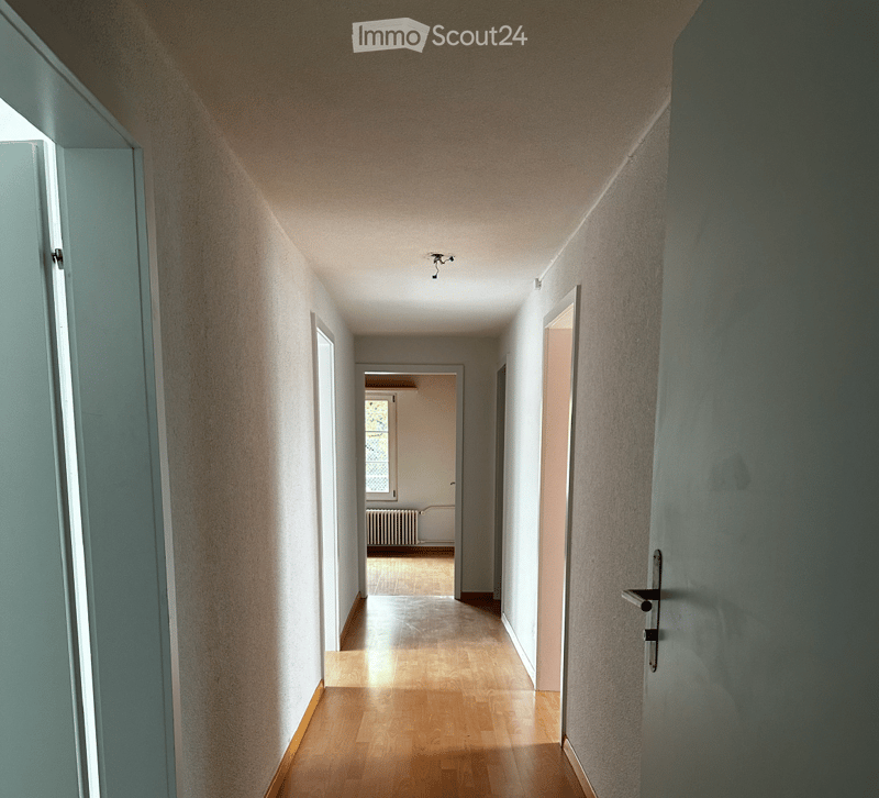 Wooden floor, white walls, small hallway leading to rooms and bathroom