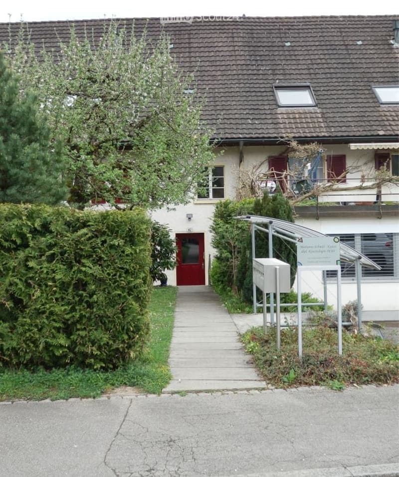 2 story house, brown roof, red door, white walls, hedges, walkway, mailbox