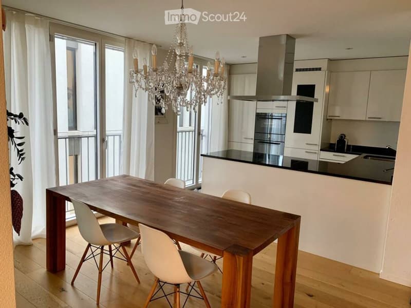 dining table with four chairs, chandelier, white walls, wooden floor, balcony with railings