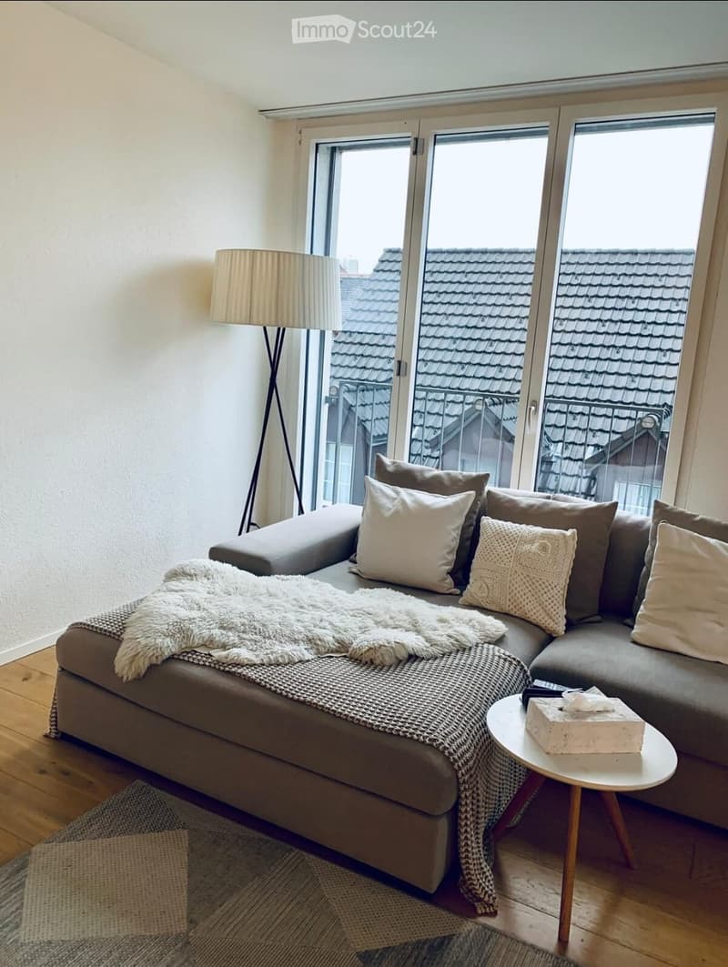 Living room: couch, lamp, coffee table, rug, windows, balcony