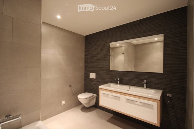 wall tiles, ceiling lights, vanity with sink, mirror, toilet, washing machine