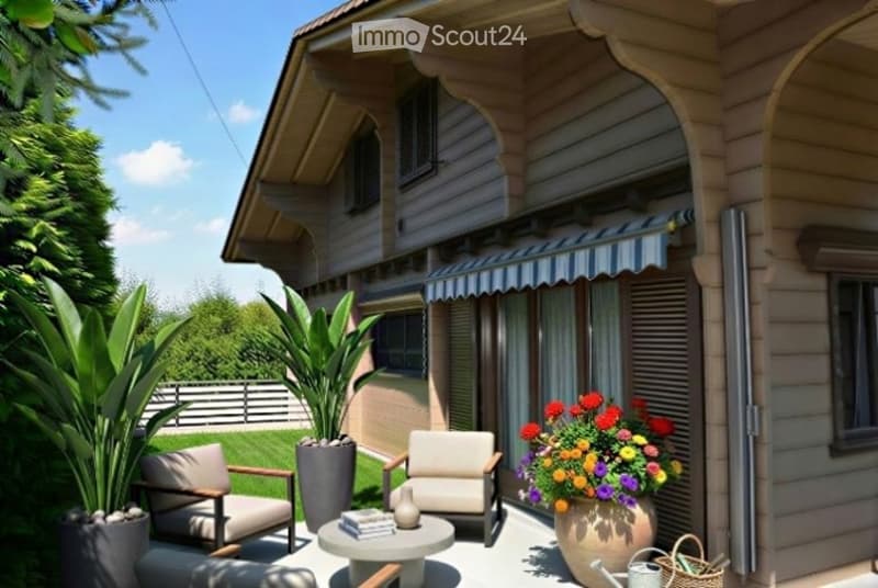 A well-maintained patio area with two armchairs, a small round table, and a vase of colorful flowers. The patio is adjacent to a house with a striped awning and is surrounded by lush greenery and potted plants.