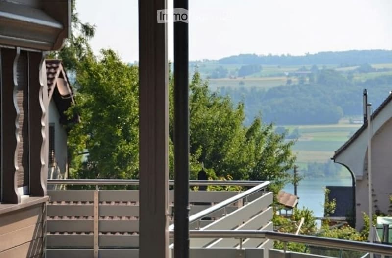 Balcony overlooking a scenic countryside with trees and distant hills.