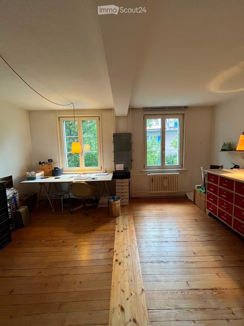 Bright room with wooden flooring, large windows, a desk with a chair, a lamp, a cabinet, and a printer.