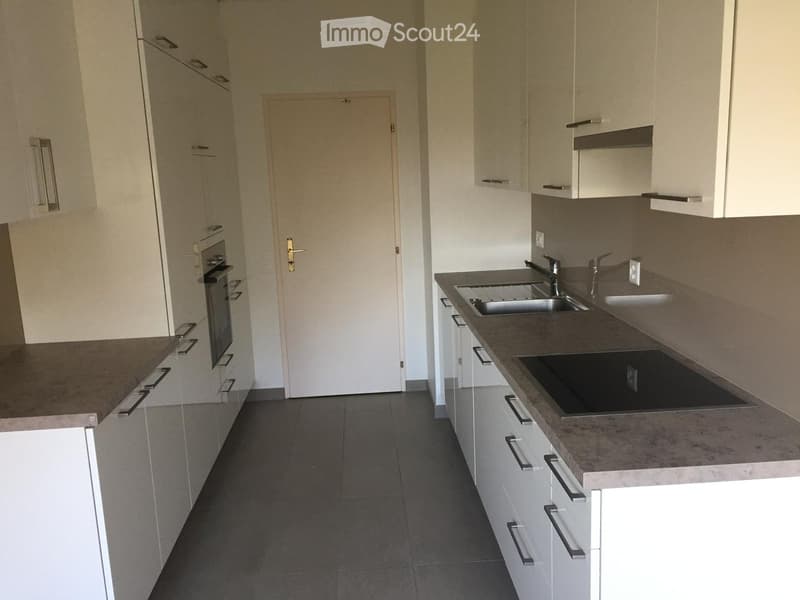 Modern kitchen with white cabinets, granite countertops, and stainless steel sink and oven.