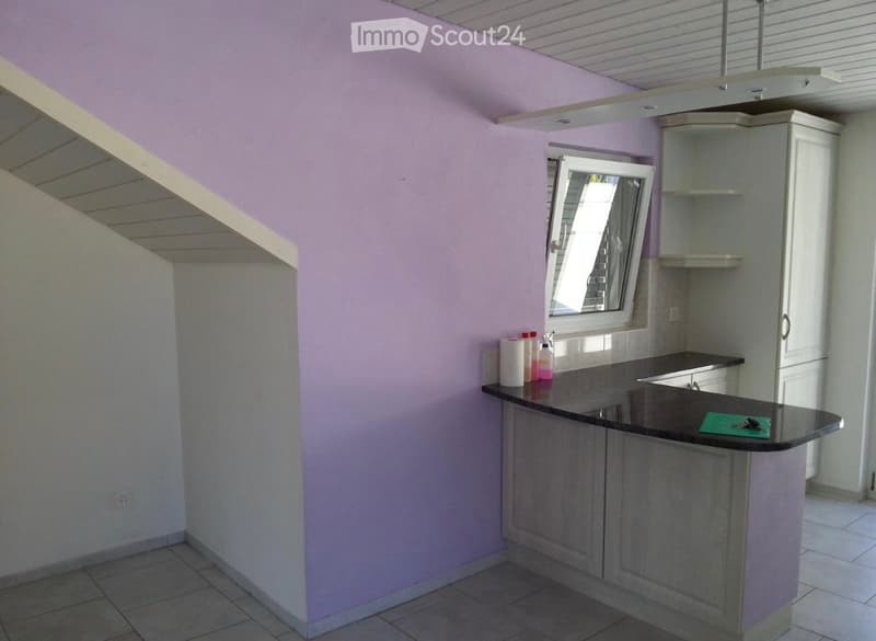 Modern kitchen with light purple walls, grey cabinets, black countertop, and a window above the sink.