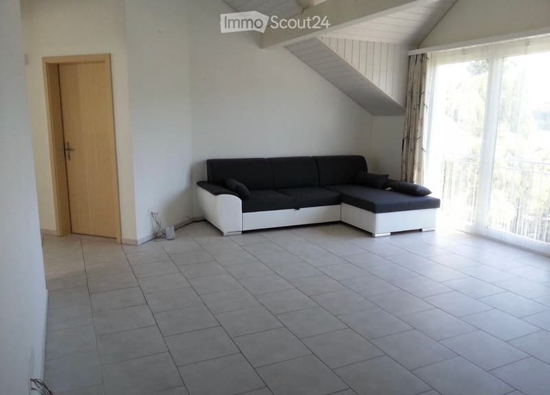 Living room with a modern black and white sectional sofa, tiled floor, large window with curtains, and a wooden door.