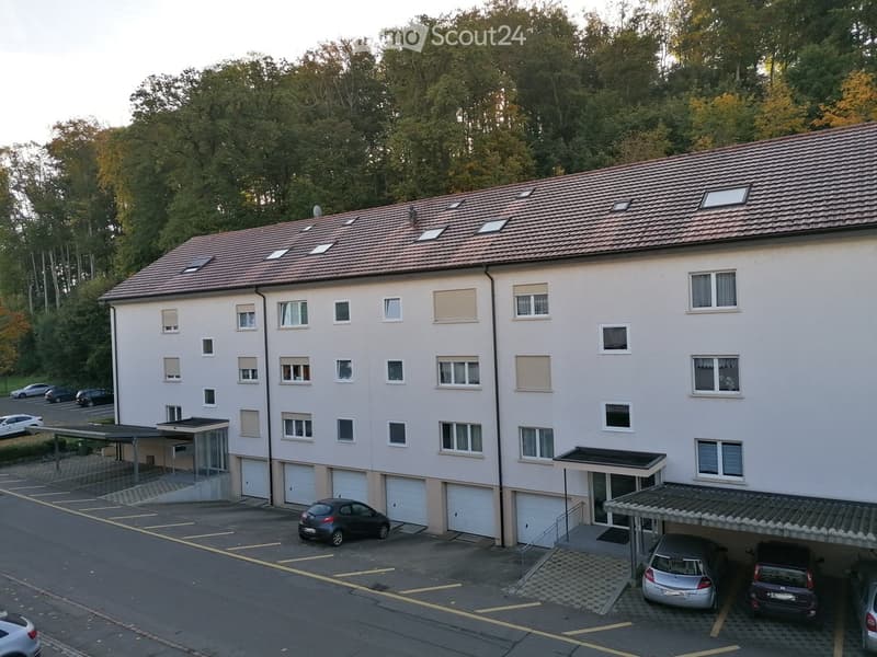 white building, multiple garages, multiple windows, large parking lot