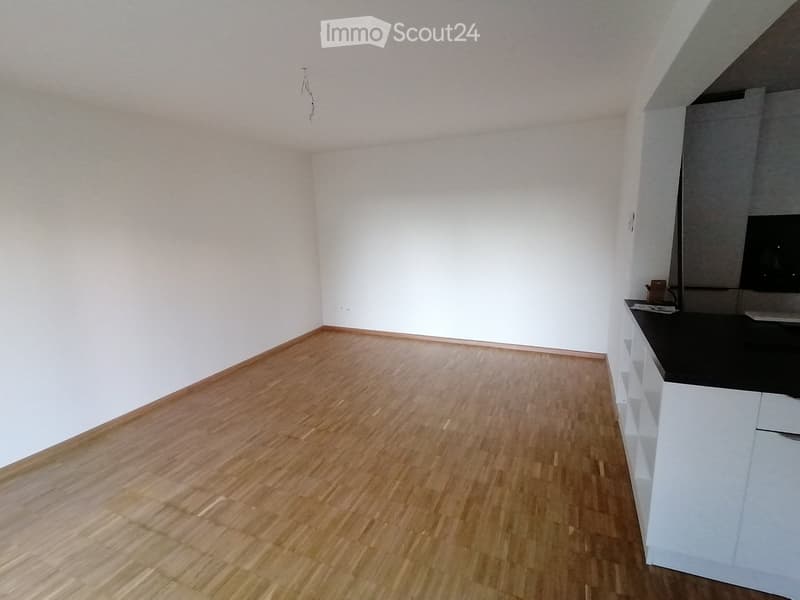 empty room, wooden floor, white walls, kitchen area