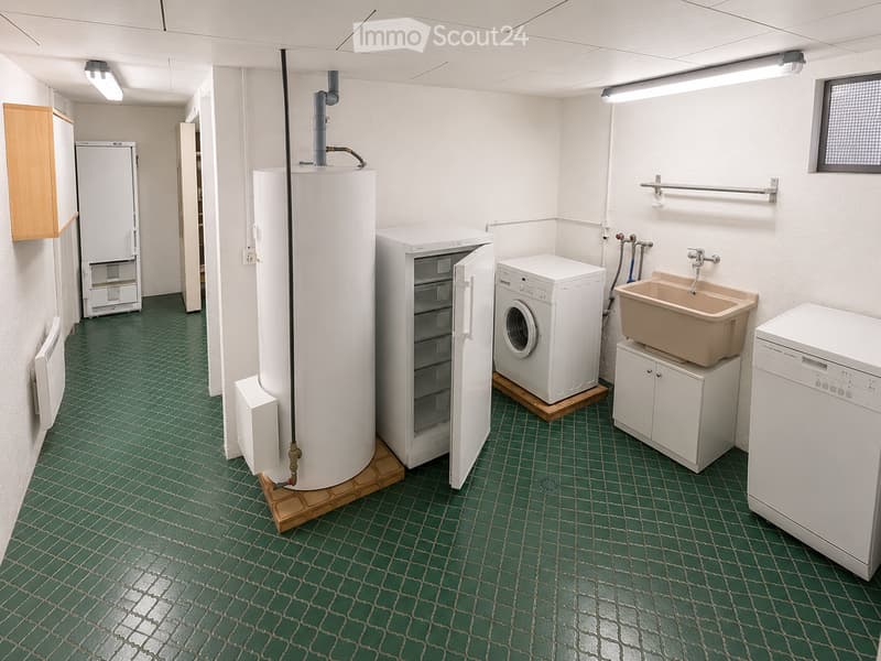 Utility room with green tiled floor, white walls, and various appliances including a washing machine, dishwasher, refrigerator, water heater, and sink.
