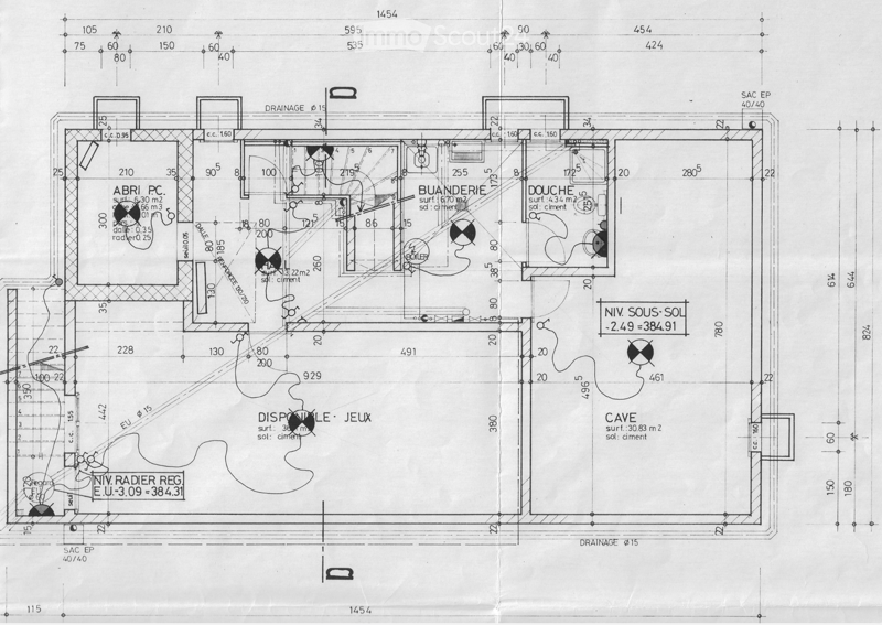 Floor plan of a basement level showing rooms labeled: Abri PC, Buanderie, Douche, Cave, and Dispoile-Jeux. Includes measurements, drainage lines, and floor levels.