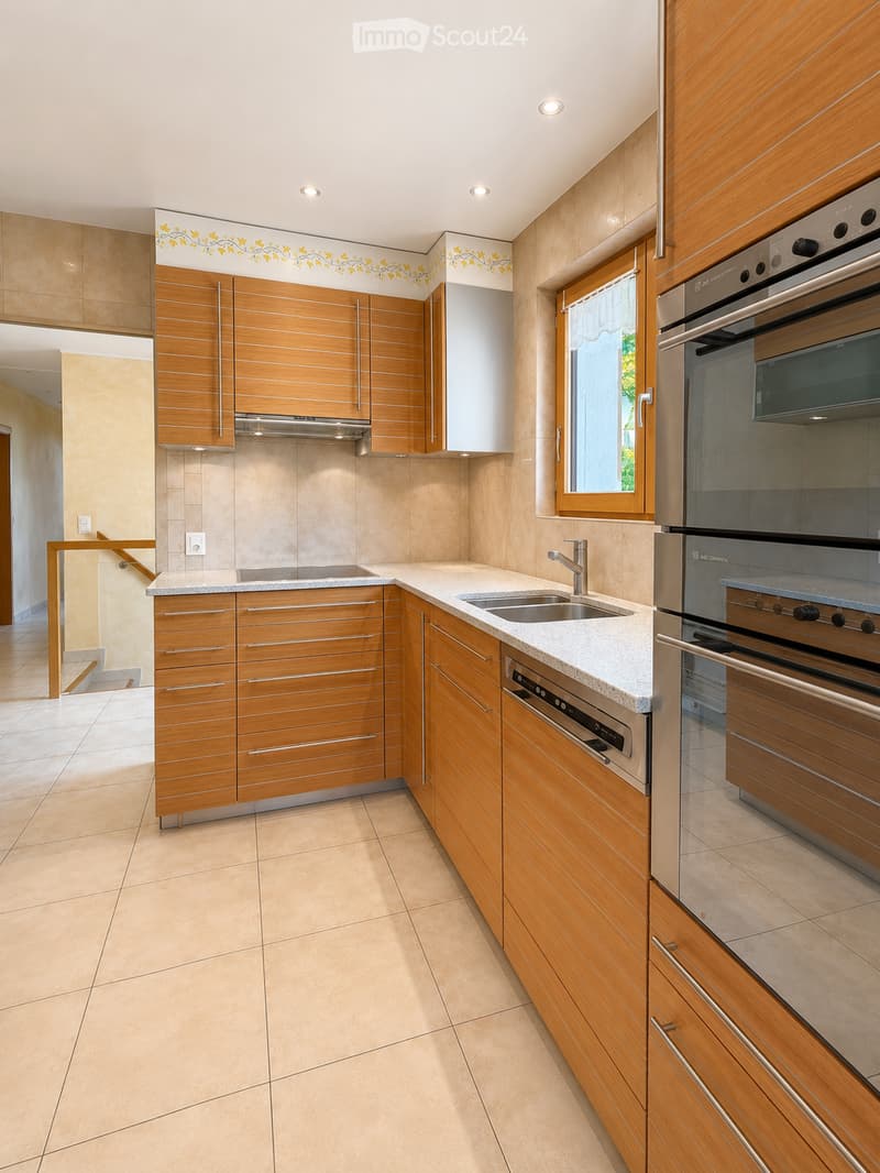 Modern kitchen with wooden cabinets, stainless steel appliances, granite countertops, and a double sink.