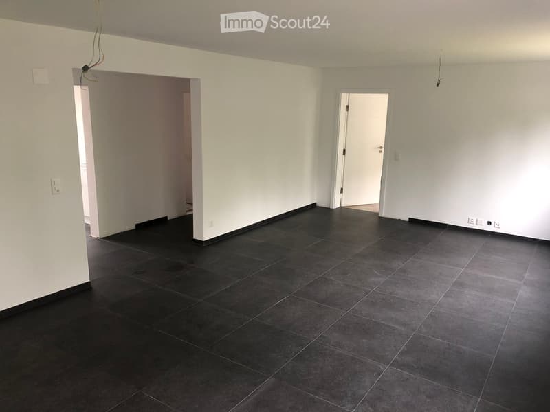 Empty room with dark tiled floor and white walls, featuring two doorways leading to adjacent spaces.