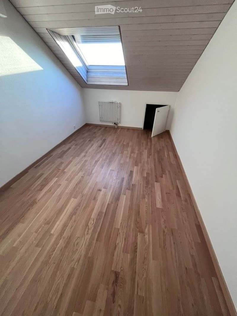 Empty room with wooden flooring, white walls, a small window, and a radiator. No furniture or equipment present.