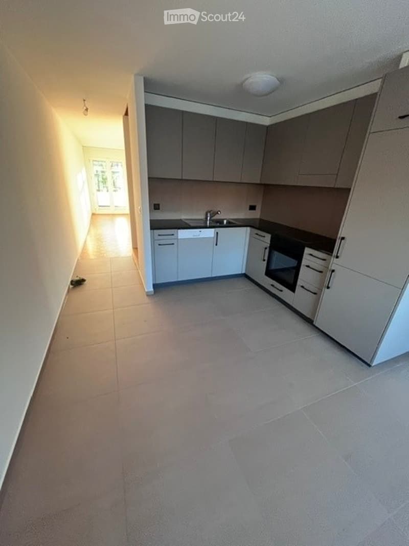 Modern kitchen with white cabinets, a sink, and an oven. The floor is tiled, and the walls are painted in a neutral tone.