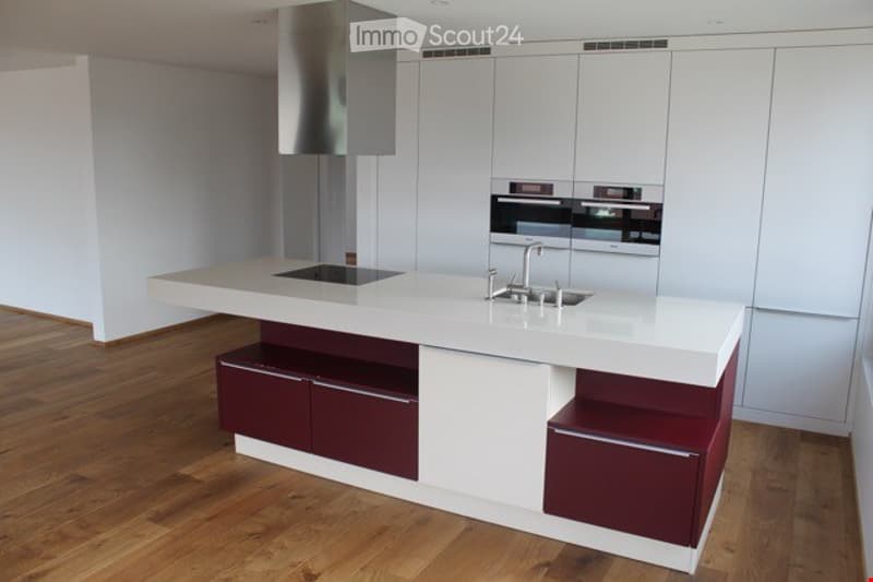 Modern kitchen with white cabinets, a central island, and stainless steel appliances including a sink and oven.