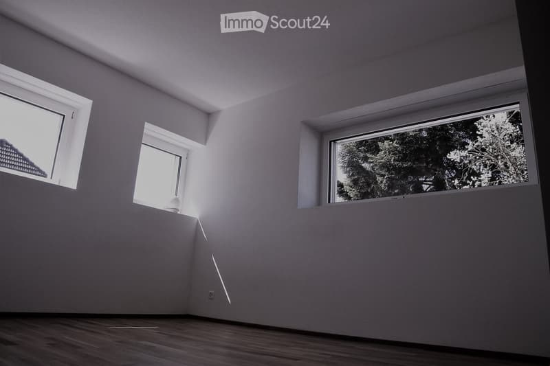 Empty room with wooden flooring, white walls, and three windows allowing natural light. No furniture or equipment present.