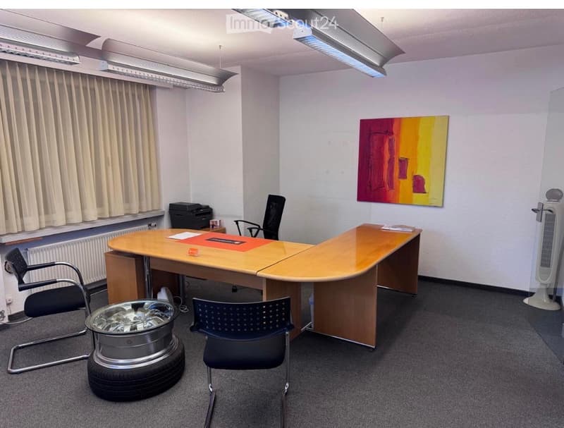 Office space with a large wooden desk, several chairs, a printer, a fan, and a colorful painting on the wall.