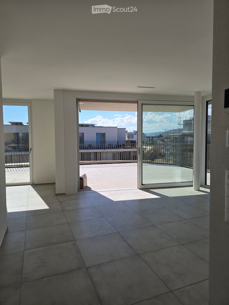 Empty room with tiled floor, large sliding glass doors leading to a balcony, and modern interior design.