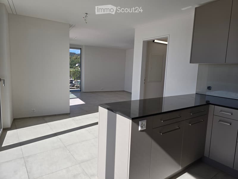 Modern kitchen with grey cabinets, black countertop, and tiled floor. Features a large window with a scenic view.