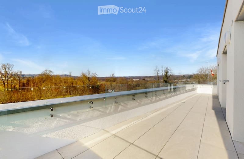 Modern balcony with glass railing, tiled floor, and scenic countryside view.