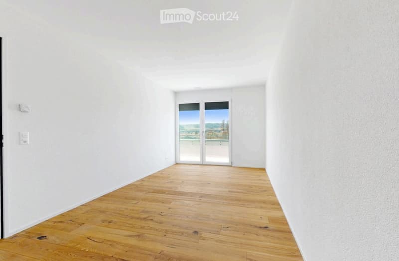 Empty room with wooden flooring, white walls, and large glass doors leading to a scenic outdoor view.