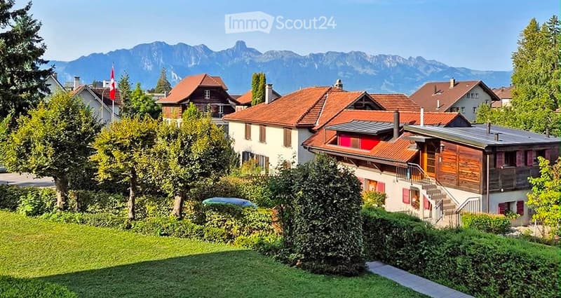 Residential neighborhood with multiple houses, red-tiled roofs, and a scenic mountain view in the background.