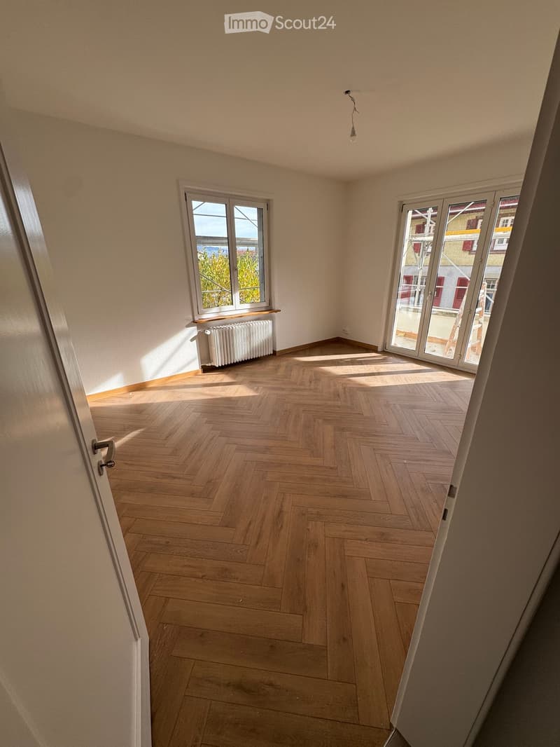 empty room, wooden parquet floor, white walls, two windows, white radiator