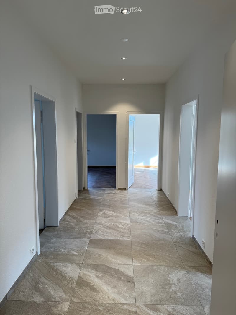 Empty hallway, four rooms visible, tiled floor, white walls, recessed lighting