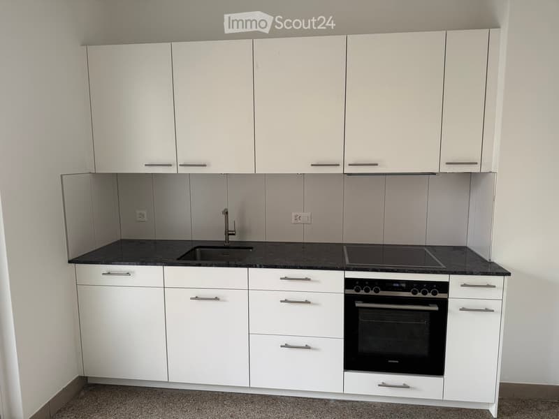 Modern kitchen with white cabinets, granite countertops, stainless steel sink, gas stove, oven, dishwasher, and washing machine.