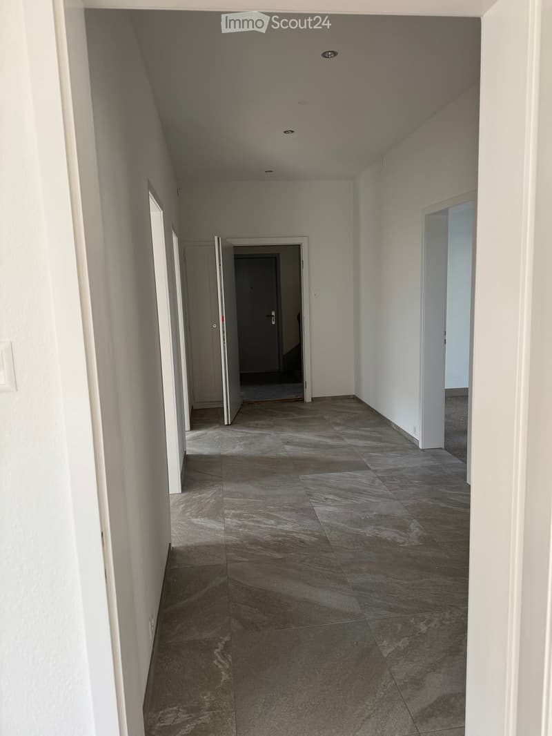 Empty hallway with tiled floor and doors leading to different rooms