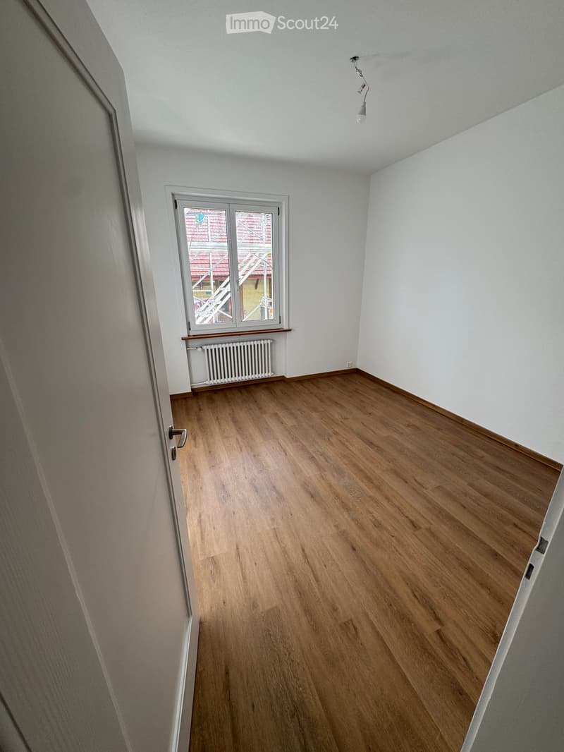 empty room, white walls, wooden floor, single window, white radiator