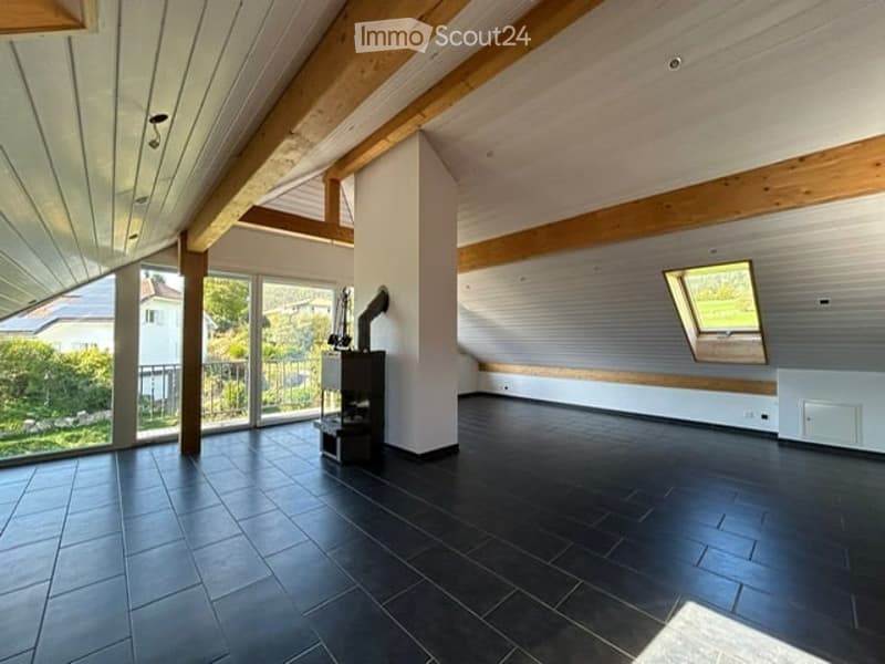 Bright, open room with exposed wooden beams, large windows, and a tiled floor. The space is completely empty, with no furniture or equipment visible.